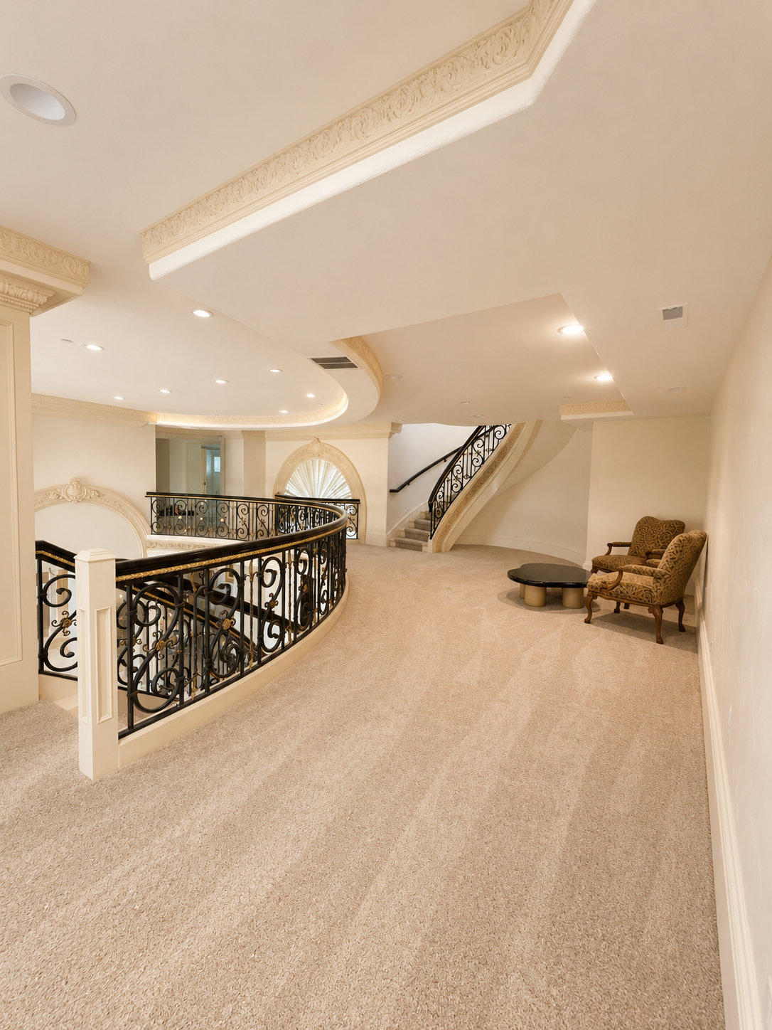 Completed upstairs landing with curved wrought-iron and gold-leaf railing, ornate plaster cornice, and arched window