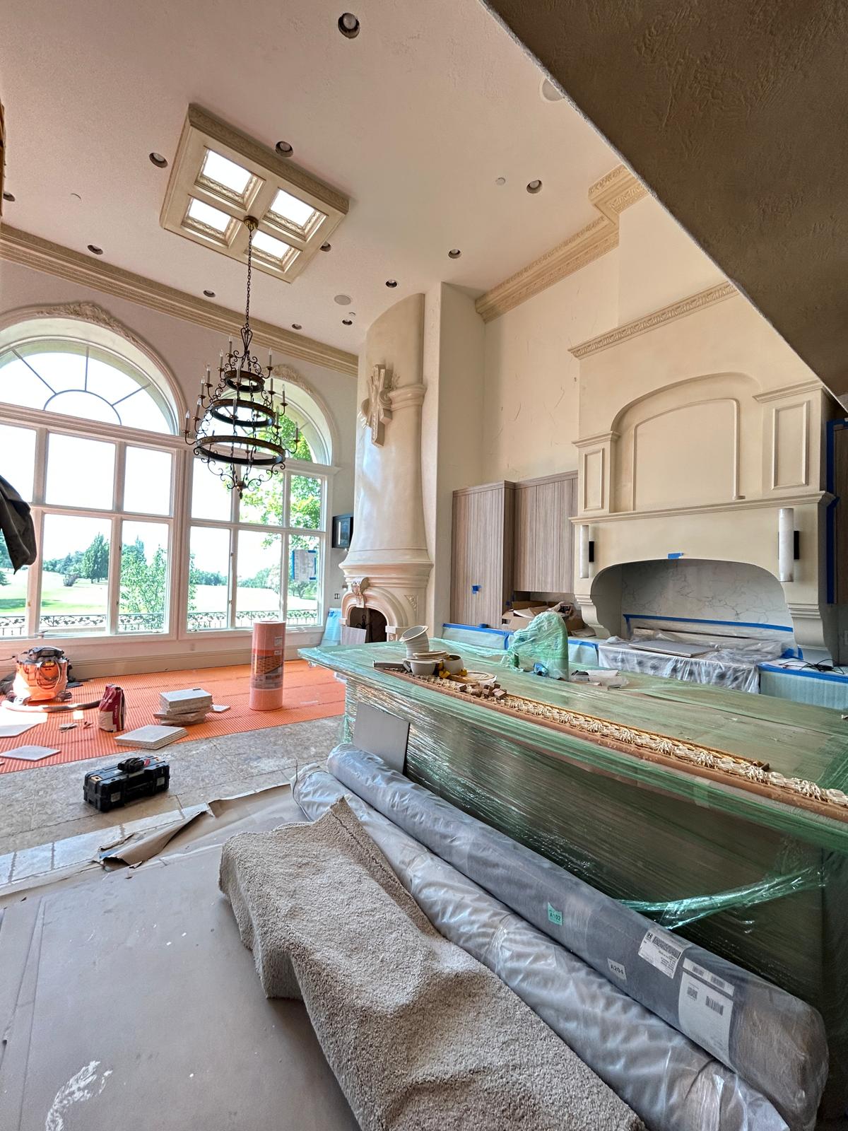 Custom kitchen island, natural stone countertops, and ornate range hood surround under finish installation