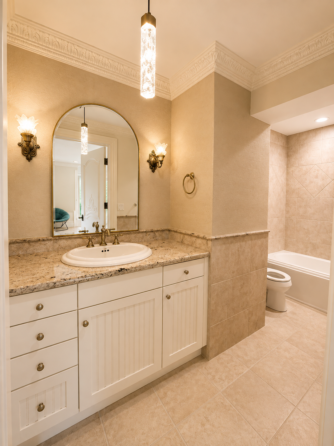 Completed upstairs bathroom with granite vanity, arched brass mirror, ornate plaster cornice, and tiled tub surround