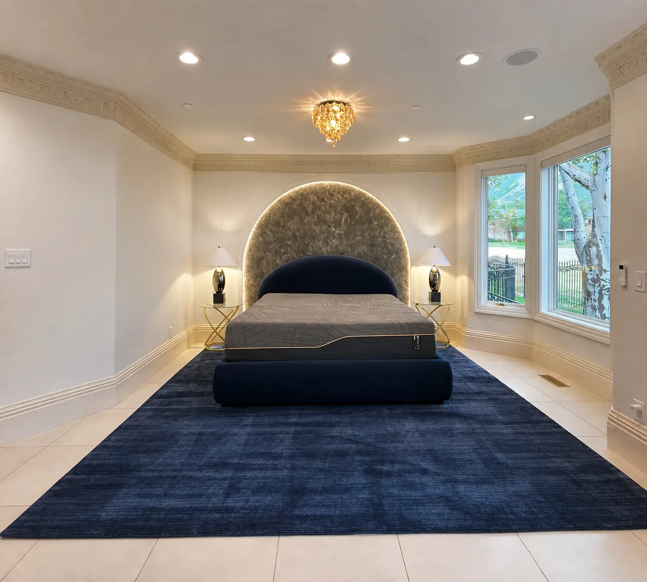 Completed primary bedroom with arched upholstered headboard wall, crown molding, and bay windows