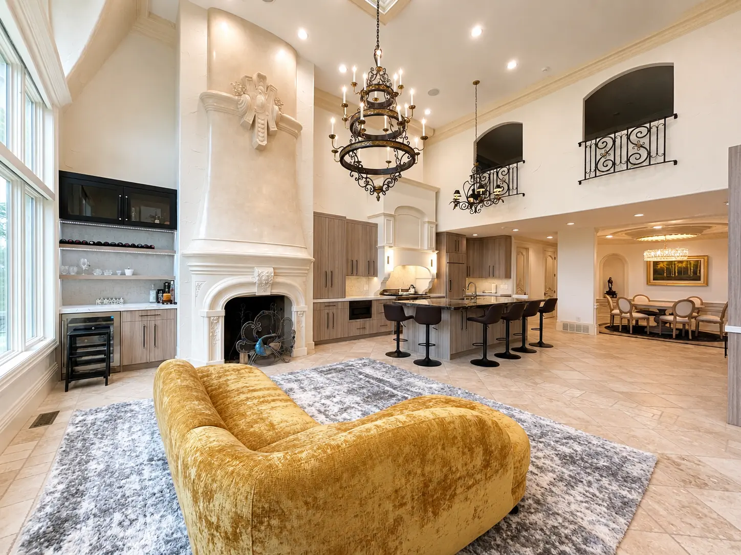 Completed great room and kitchen with cast-stone fireplace, iron chandeliers, and open second-floor balconies